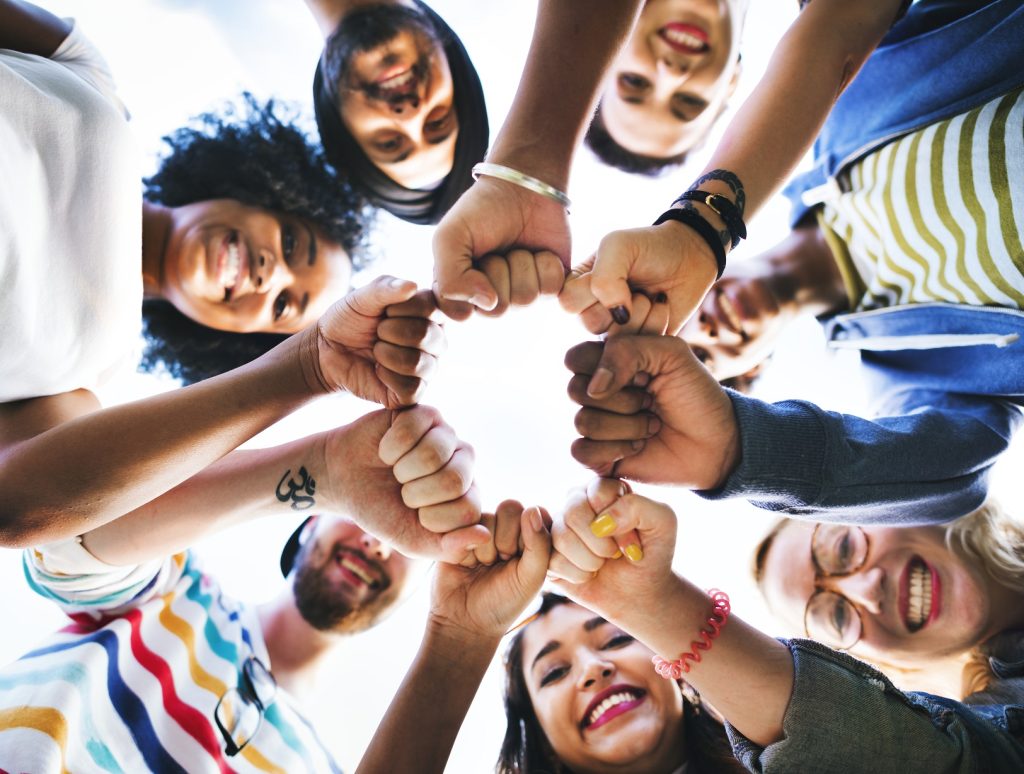 Picture of a group of friends chop knuckling in a circle.