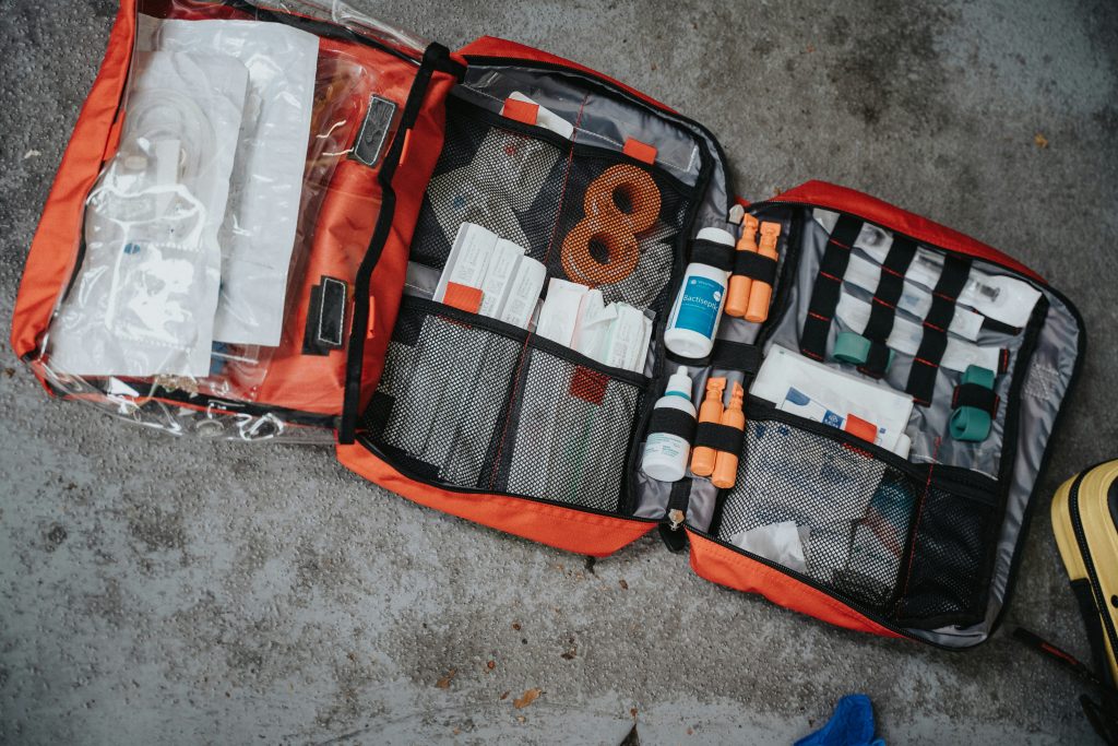 Open emergency medical kit on the ground, displaying various medical supplies such as bandages, bottles of antiseptic solution, medical tape, and other first aid essentials organized in a red and black bag.

This image shows what a well equipped first-aid kit looks like. And this is an important item to have as part of thr safety tips for traveling abroad.

